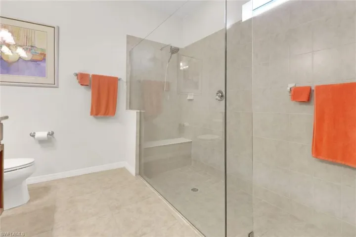 Primary Bathroom with tile patterned floors, vanity, toilet, and a tile shower