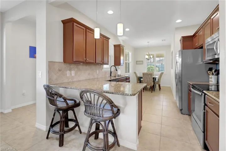 Kitchen featuring kitchen peninsula, stainless steel appliances, hanging light fixtures, and tasteful backsplash