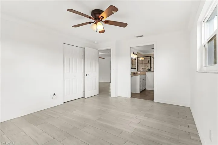 Unfurnished bedroom with crown molding, light wood-style flooring, ceiling fan, a closet, and connected bathroom