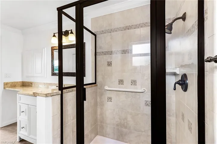 Bathroom featuring a shower stall, vanity, and ornamental molding