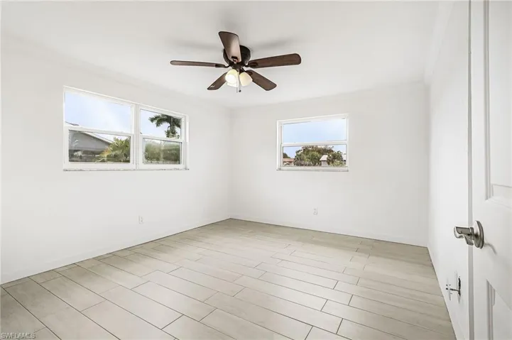 Empty room featuring a ceiling fan, crown molding, and light wood-type flooring