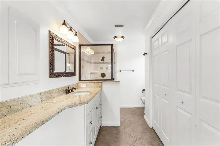 Bathroom with vanity, a walk in shower, crown molding, a closet, and light tile patterned flooring