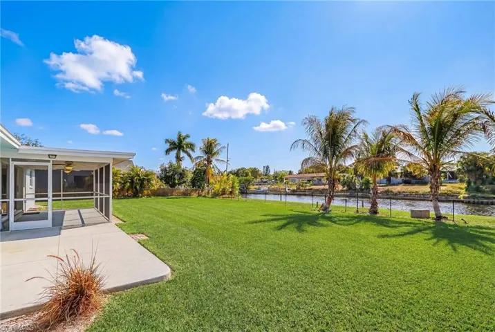 View of grassy yard with a sunroom and a water view