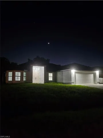 View of front of property featuring a yard, a garage, and driveway