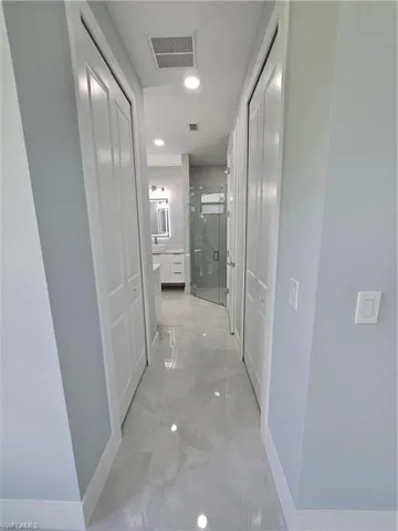 Hall with recessed lighting and light marble finish floors