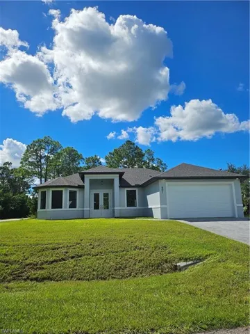 Prairie-style home featuring stucco siding, a garage, driveway, french doors, and a front yard