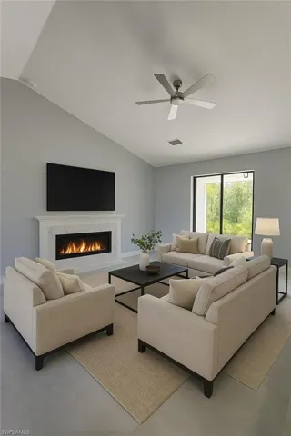 Living room with a high end fireplace, vaulted ceiling, a ceiling fan, and finished concrete flooring