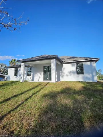 Back of house with stucco siding and a lawn