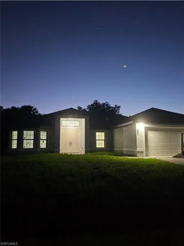 Ranch-style home featuring a garage and a front lawn