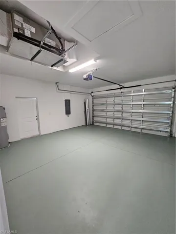 Garage featuring water heater, electric panel, and a garage door opener