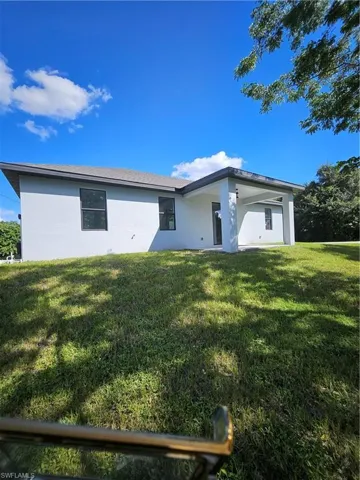 Rear view of house with a lawn and stucco siding