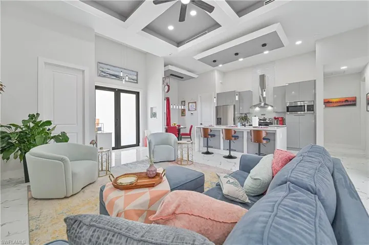 Living area featuring recessed lighting, coffered ceiling, a towering ceiling, marble finish floor, and french doors