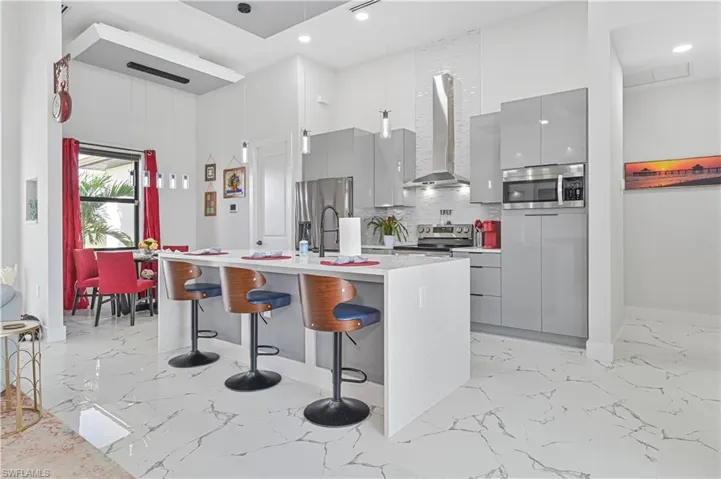 Kitchen with marble finish floor, wall chimney exhaust hood, modern cabinets, and gray cabinetry