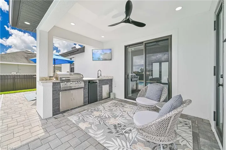 View of patio with a sink, fence, a ceiling fan, exterior kitchen, and grilling area