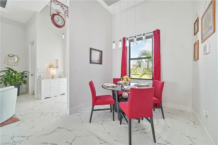 Dining room featuring marble finish floor, a towering ceiling, and baseboards