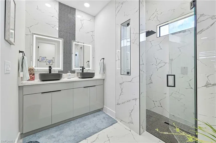 Bathroom with marble finish floor, double vanity, a sink, and a marble finish shower