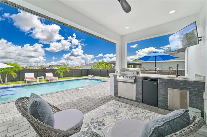 View of pool with exterior kitchen, a fenced backyard, a sink, and grilling area