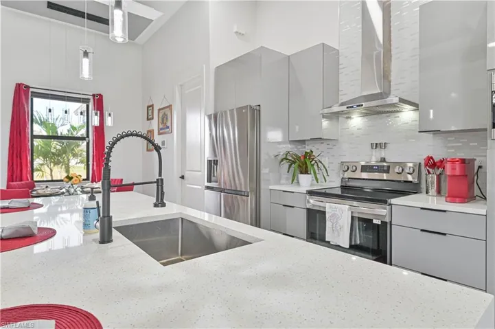 Kitchen with stainless steel appliances, wall chimney range hood, gray cabinetry, and modern cabinets