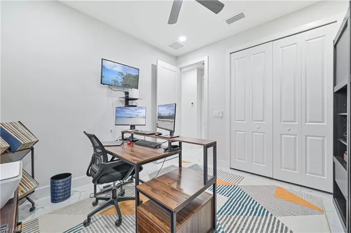Office space with a ceiling fan, marble finish floor, visible vents, and baseboards