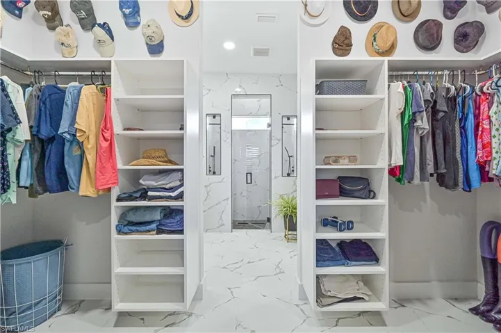 Spacious closet featuring marble finish floor and visible vents