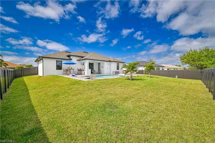 Rear view of property with a fenced in pool, stucco siding, a lawn, a patio area, and a fenced backyard