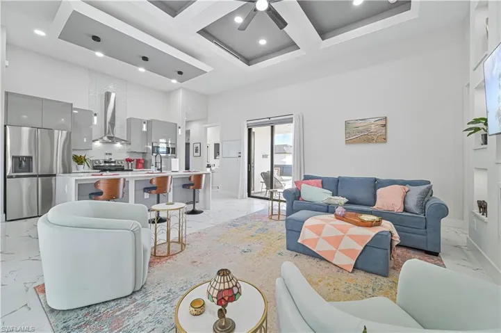 Living area with recessed lighting, a high ceiling, coffered ceiling, marble finish floor, and beam ceiling