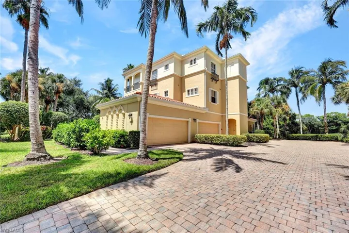 View of side of property with decorative driveway, stucco siding, an attached garage, and a yard