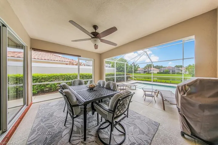 Screened patio with a built-in ceiling fan, textured flooring, and a swimming pool