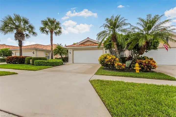 Single-story stucco exterior with a tile roof, two-car garage, concrete driveway, and mature palm trees