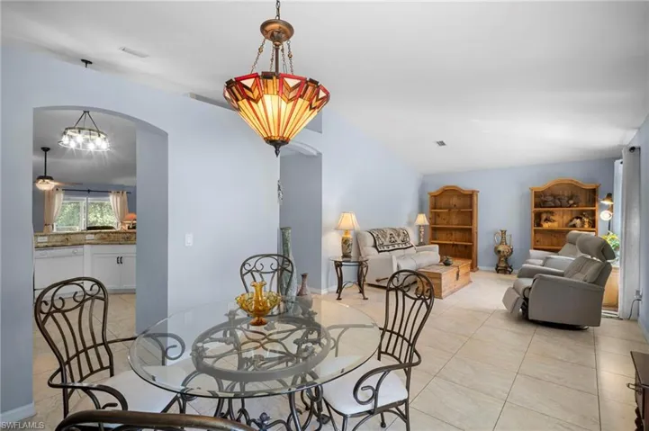 Dining room featuring arched walkways, light tile patterned flooring, a chandelier, lofted ceiling, and ceiling fan
