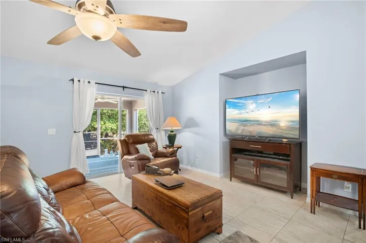Living room featuring lofted ceiling, ceiling fan, and light tile patterned floors
