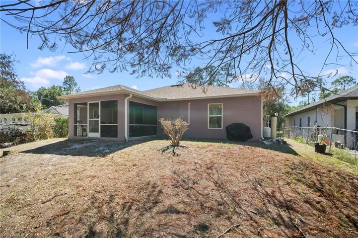 Rear view of house featuring a sunroom, stucco siding, and roof with shingles