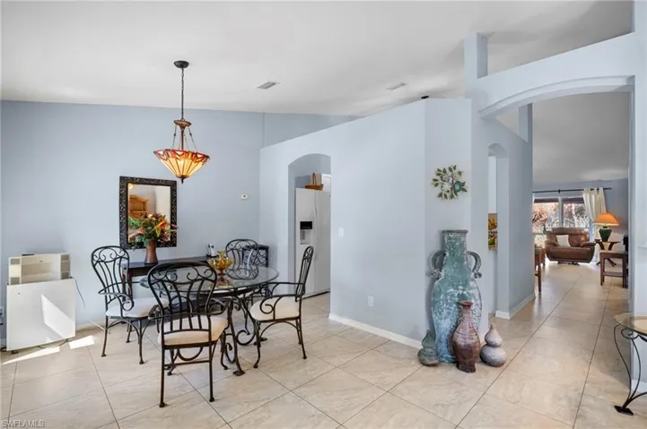 Dining area with arched walkways, lofted ceiling, and light tile patterned flooring