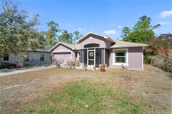 View of front of house with a garage, driveway, stucco siding, a front yard, and a sunroom