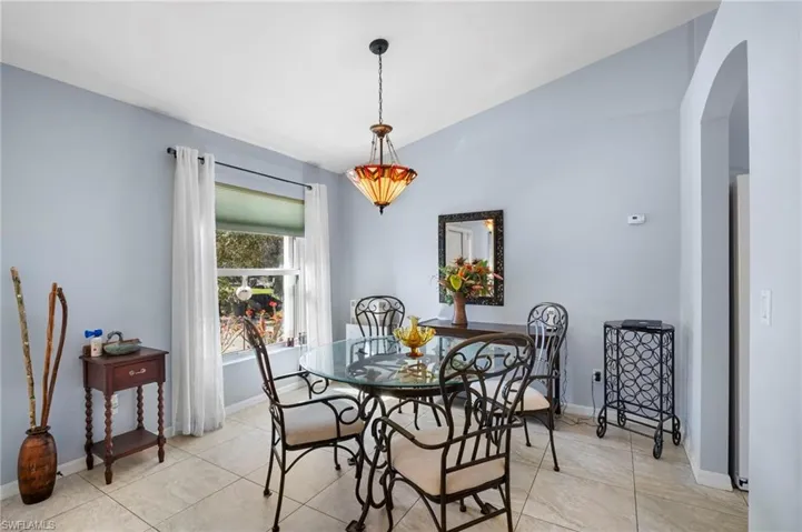 Dining room featuring lofted ceiling, arched walkways, and light tile patterned floors
