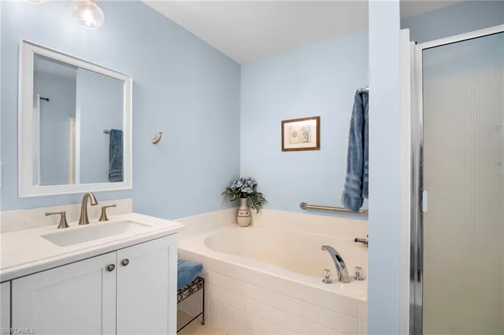 Bathroom featuring vanity, a garden tub, and a stall shower