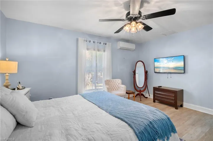 Bedroom featuring wood finished floors, a mini split for heating / cooling, and ceiling fan