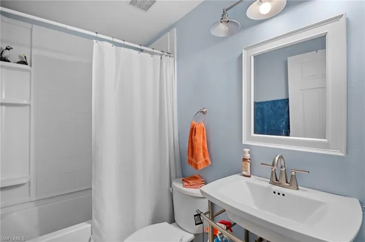 Bathroom featuring toilet and shower / tub combo with curtain