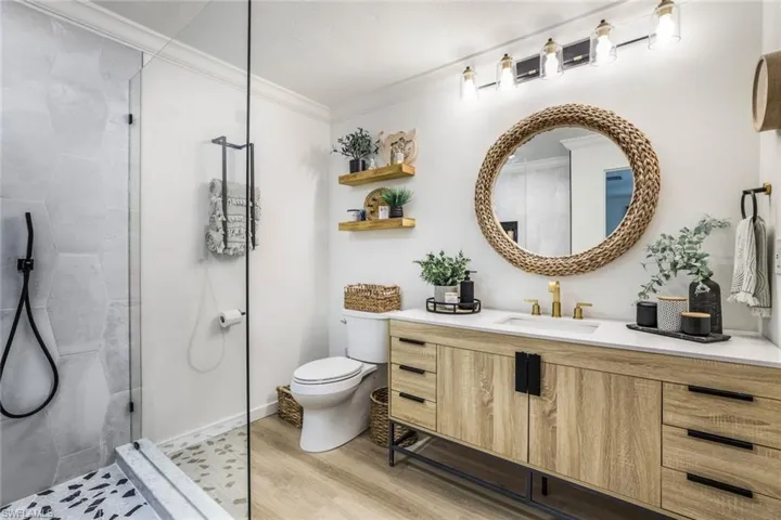 Bathroom featuring toilet, walk in shower, ornamental molding, vanity, and hardwood / wood-style flooring