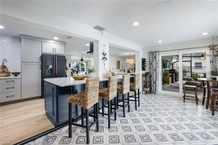 Kitchen featuring light wood-type flooring, high end fridge, a kitchen bar, kitchen peninsula, and gray cabinetry