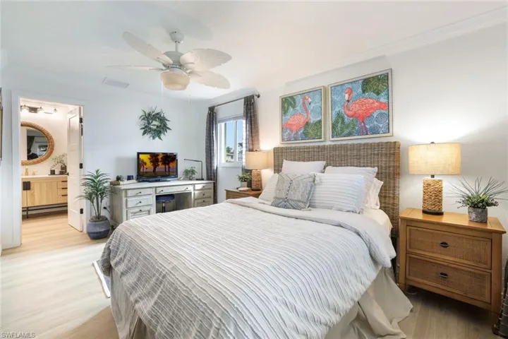 Bedroom featuring ceiling fan, light hardwood / wood-style floors, crown molding, and ensuite bath
