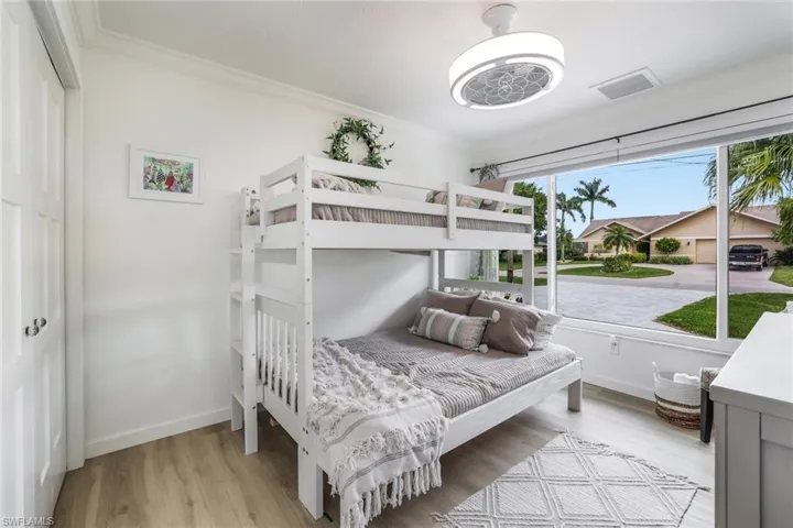 Bedroom with crown molding, multiple windows, and light hardwood / wood-style flooring