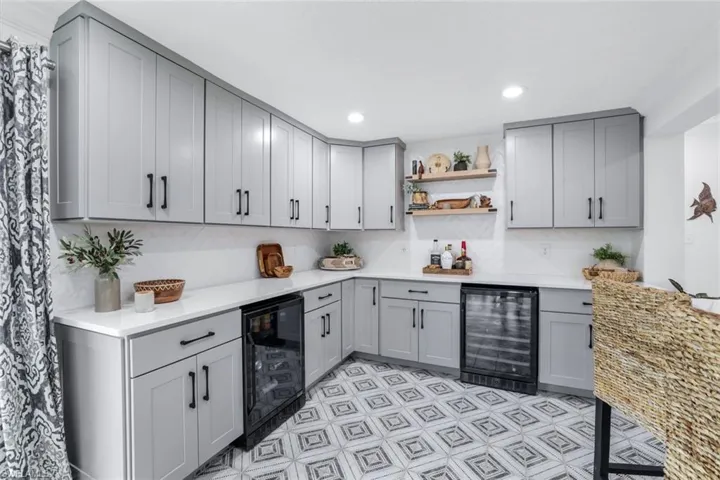 Kitchen with tasteful backsplash, wine cooler, and gray cabinetry