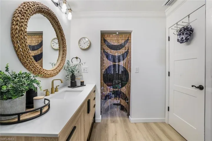 Bathroom featuring ornamental molding, vanity, and hardwood / wood-style floors