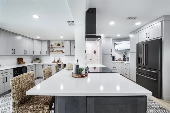 Kitchen featuring black appliances, a center island, gray cabinetry, a breakfast bar area, and extractor fan