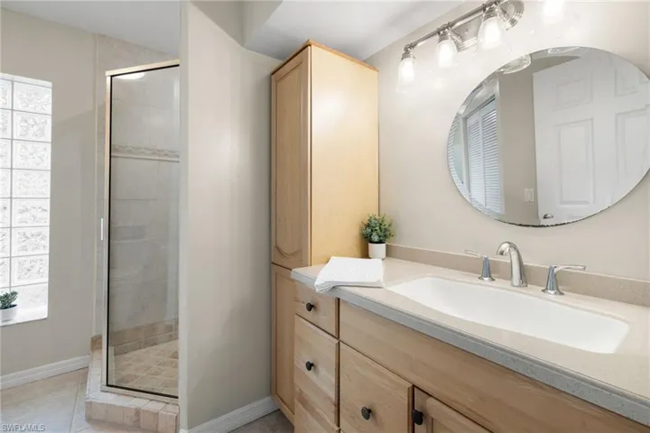 Bathroom with tile patterned flooring, a shower stall, vanity, and baseboards