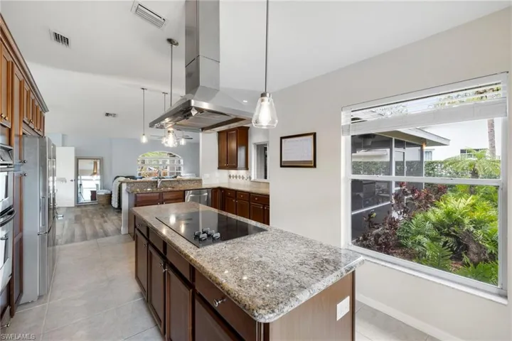 Kitchen featuring decorative light fixtures, island exhaust hood, stainless steel appliances, visible vents, and a kitchen island