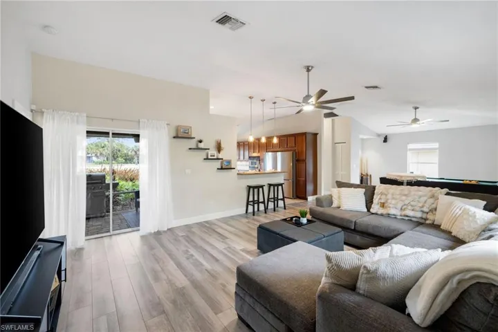 Living room featuring pool table, visible vents, light wood-style flooring, vaulted ceiling, and baseboards