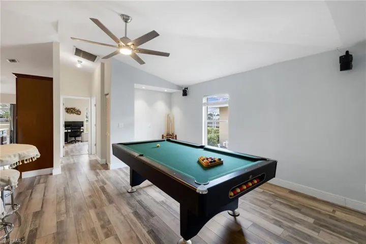 Recreation room with lofted ceiling, visible vents, and wood finished floors