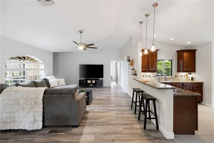 Living area featuring recessed lighting, a ceiling fan, visible vents, vaulted ceiling, and light wood-style floors